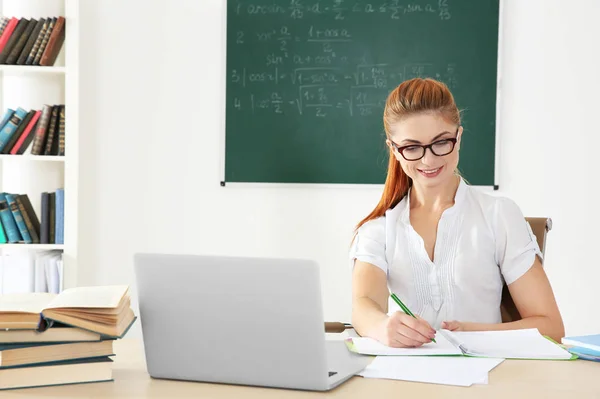 Young teacher at desk in classroom — Stock Photo, Image