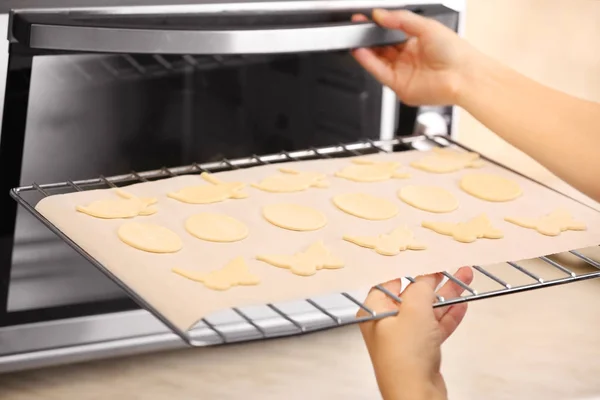 Женщина кладет пасхальные печенья в духовку — стоковое фото