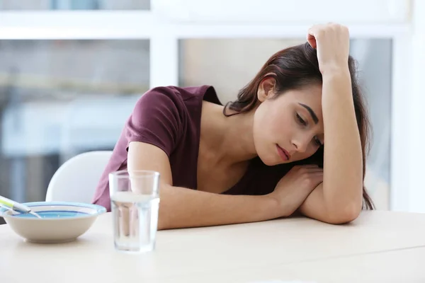 Депрессивная женщина сидит за кухонным столом без аппетита — стоковое фото