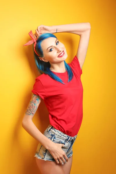Красива молода жінка зі стильним кольором волосся та татуювання на жовтому фоні — стокове фото