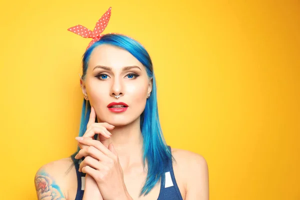 Mooie jonge vrouw met stijlvolle kleur haar en tattoo op gele achtergrond — Stockfoto