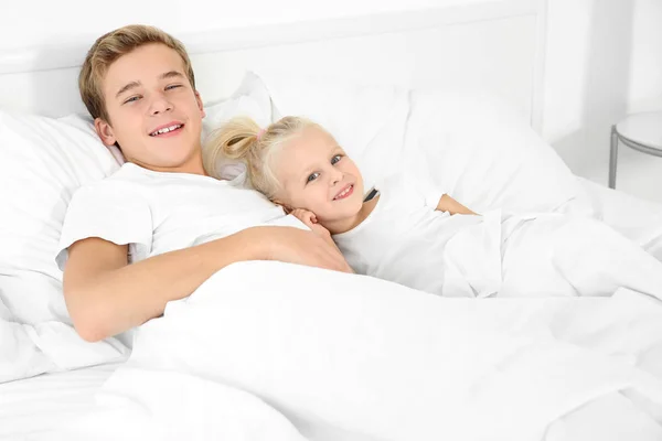 Cute little girl with elder brother lying in bed — Stock Photo, Image