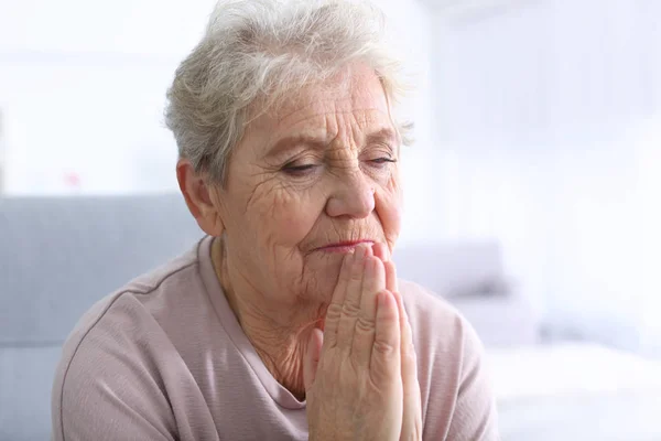 Bejaarde vrouw thuis te bidden — Stockfoto