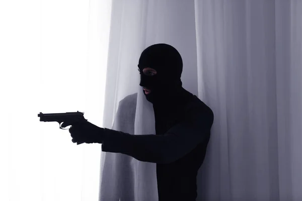 カーテンの後ろに銃を持つ男性泥棒 — ストック写真