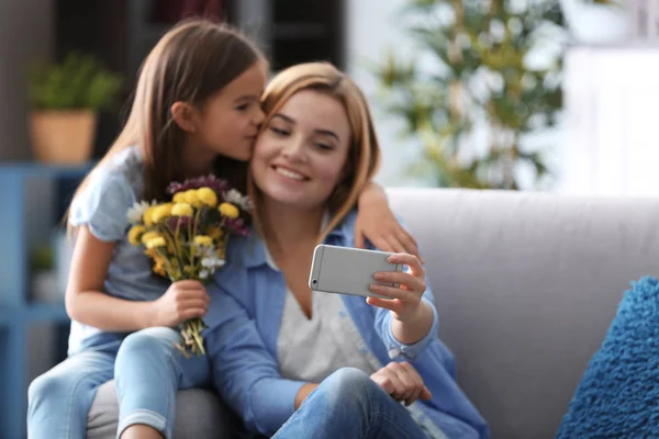 Gyönyörű fiatal nő, és ő lánya véve selfie otthon a kanapén ülve. Anyák napja-koncepció — Stock Fotó