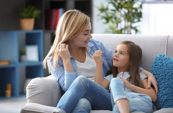 Happy young woman and her daughter sitting on sofa at home. Mother's day concept — Stock Photo, Image