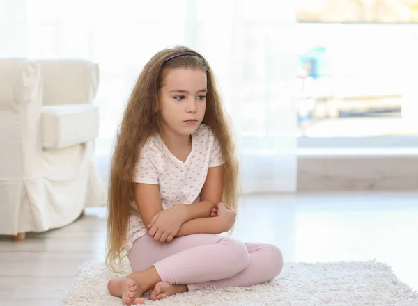 Verdrietig meisje, zittend op de vloer in de kamer — Stockfoto