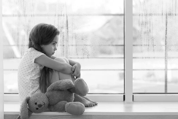 Menina triste sentada no peitoril da janela — Fotografia de Stock