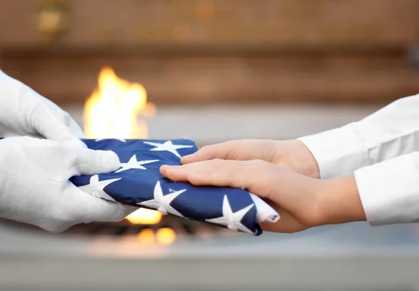 Handen met gevouwen Amerikaanse vlag — Stockfoto