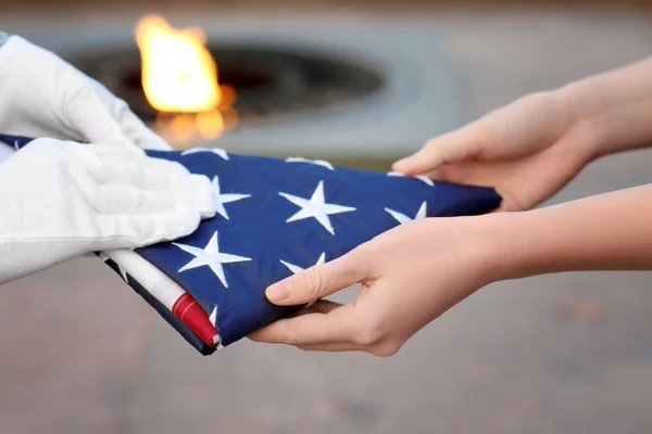 Hands holding folded American flag