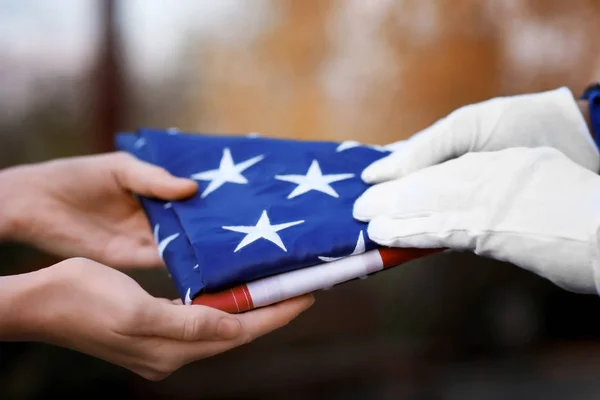 Hands holding folded American flag