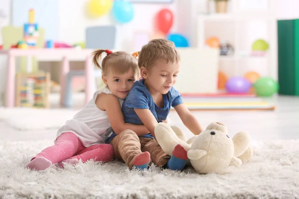 Leuke grappige kinderen spelen met teddybeer thuis — Stockfoto