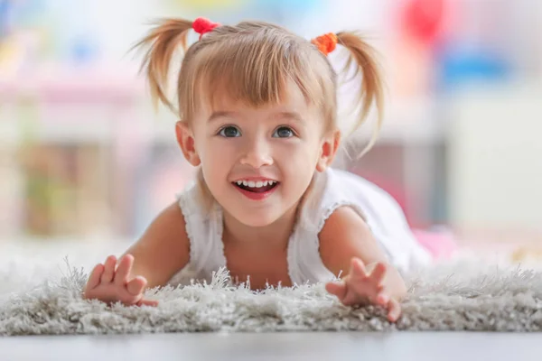 Schattig klein meisje liggend op tapijt thuis — Stockfoto