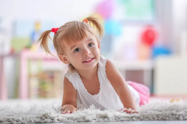 Schattig klein meisje liggend op tapijt thuis — Stockfoto