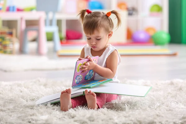 Menina bonito sentado no tapete com livros — Fotografia de Stock