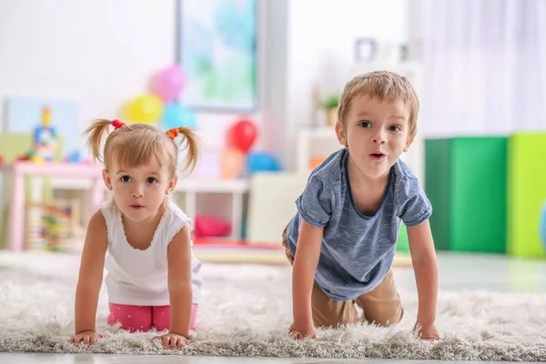 Bambini simpatici divertenti che giocano sul tappeto a casa — Foto Stock