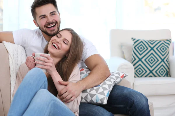 Young couple sitting on sofa — Stock Photo, Image