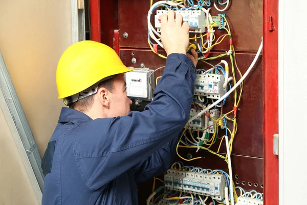 Dağıtım panosundaki telleri bağlarken elektrikçi — Stok fotoğraf