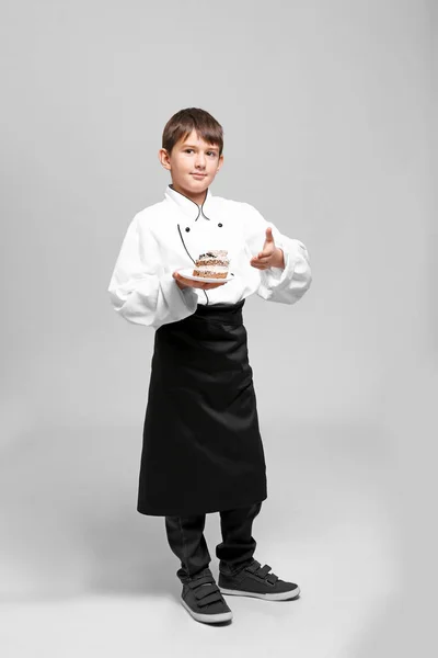 Симпатичный мальчик в форме шеф-повара на светлом фоне — стоковое фото