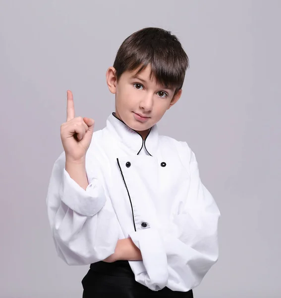 Lindo chico en uniforme de chef sobre fondo claro — Foto de Stock