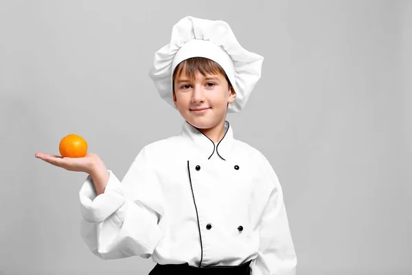 Bonito menino no chef uniforme no luz fundo — Fotografia de Stock