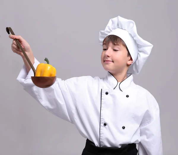 Bonito menino no chef uniforme no luz fundo — Fotografia de Stock