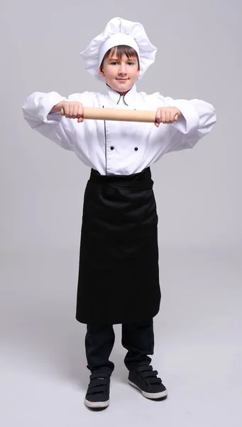 Симпатичный мальчик в форме шеф-повара на светлом фоне — стоковое фото