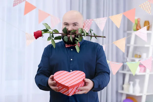 Funny fat man with giftbox and flower at birthday party