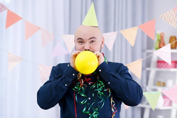 Legrační tlustý muž nafouknutí balónu na narozeninovou oslavu — Stock fotografie
