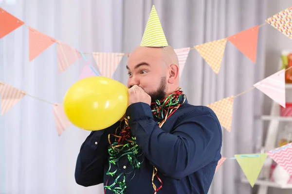 Funny fat man inflating balloon at birthday party