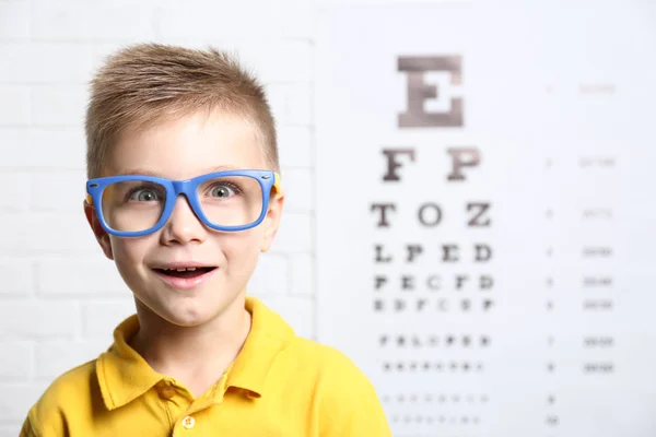 Menino com óculos no gráfico de teste oftálmico — Fotografia de Stock