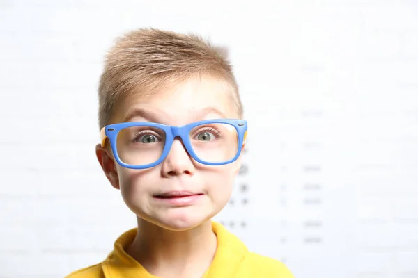 Menino com óculos no gráfico de teste oftálmico — Fotografia de Stock