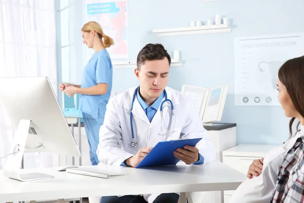Doctor filling medical record of pregnant woman