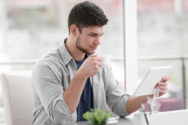 Yakışıklı genç adam evde kahve içiyor.