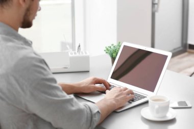 Dizüstü bilgisayarda çalışma ve evde kahve içme yakışıklı delikanlı