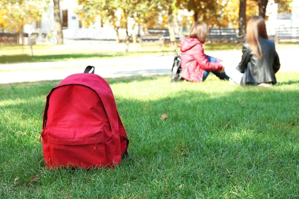 Yeşil çimenlerin üzerinde kırmızı sırt çantası — Stok fotoğraf