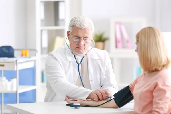 Doctor measuring blood pressure of patient — Stock Photo, Image