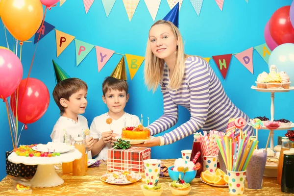 Mother with birthday cake for cute twins at party
