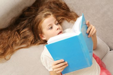 Küçük kız kanepede kitap okuma