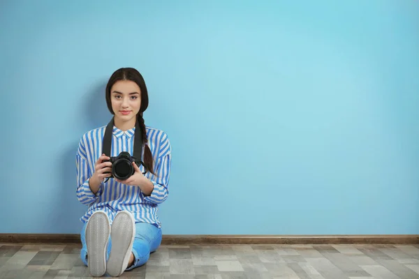 Jovem fotógrafo bonito sentado no chão perto da parede de cor — Fotografia de Stock
