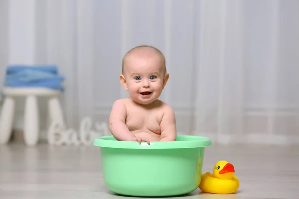 Bebê bonito na bacia de plástico — Fotografia de Stock