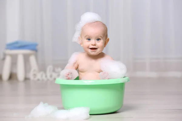 Bebê bonito na bacia de plástico — Fotografia de Stock