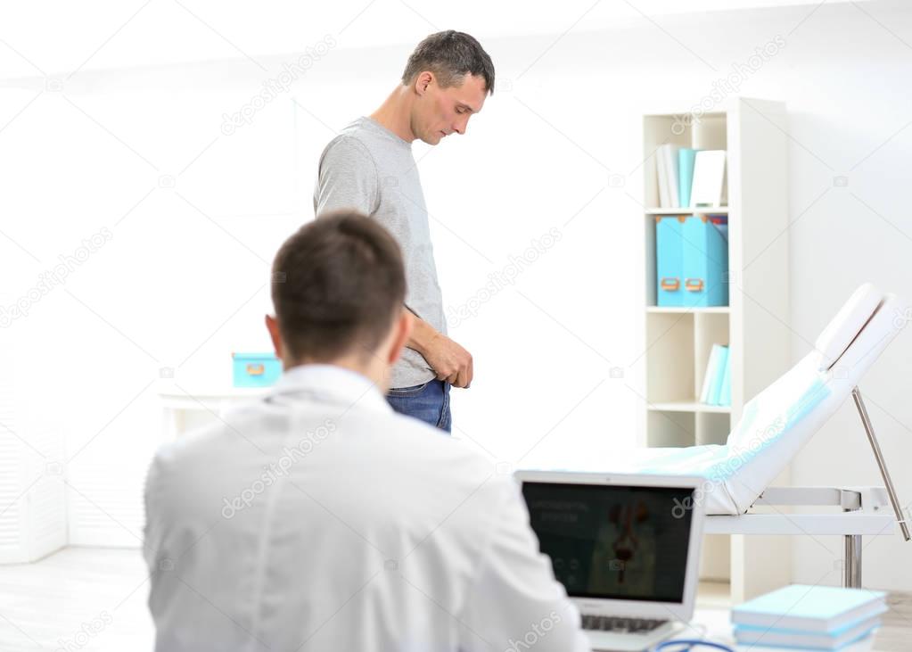 Man with health problems visiting urologist. Doctor with laptop sitting at table