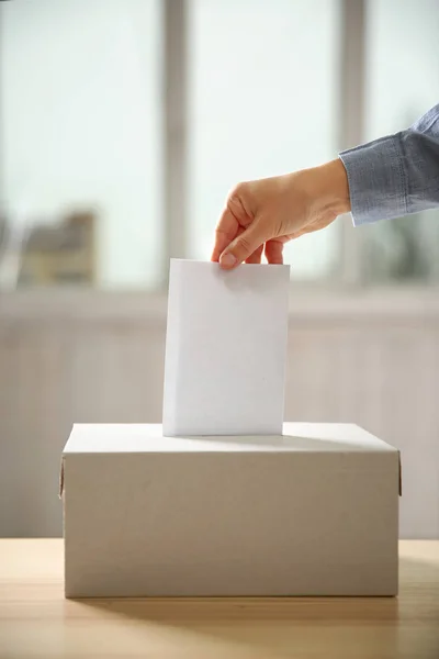 Hand inserting envelope in ballot box — Stock Photo, Image