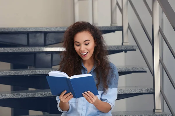 Piękna młoda kobieta siedzi na schodach i czytanie książki — Zdjęcie stockowe