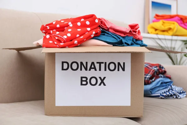 Box with clothing on sofa — Stock Photo, Image