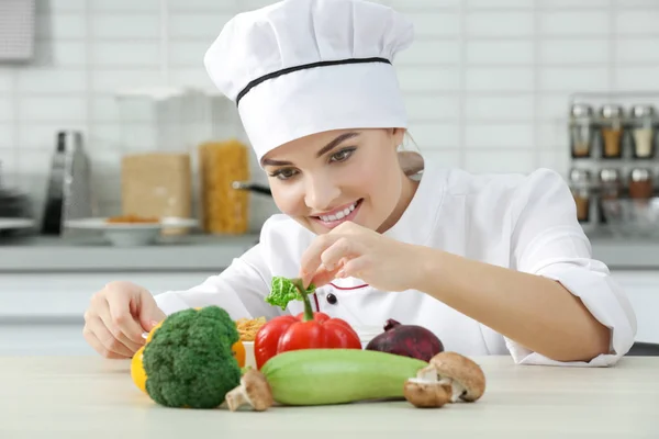 Mujer joven chef con conjunto de verduras en la mesa —  Fotos de Stock