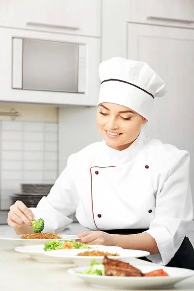 Jeune femme chef avec différents plats sur des assiettes dans la cuisine moderne — Photo