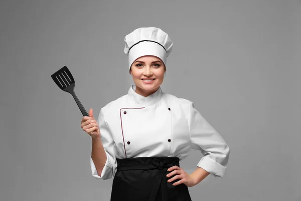 Portrait de jeune femme chef avec spatule sur fond clair — Photo