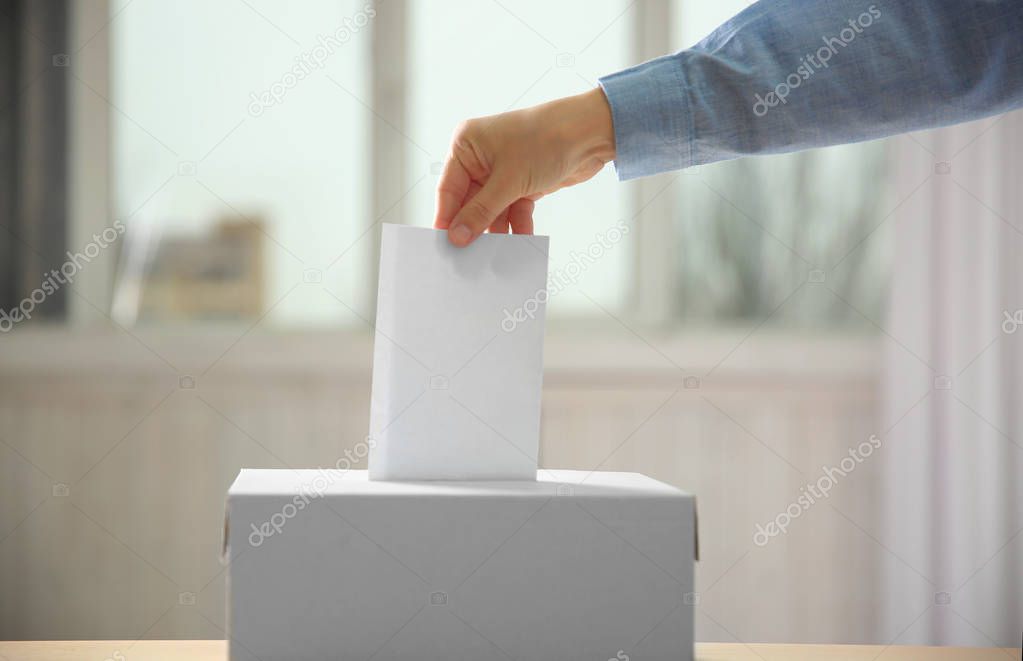 hand inserting envelope in ballot box